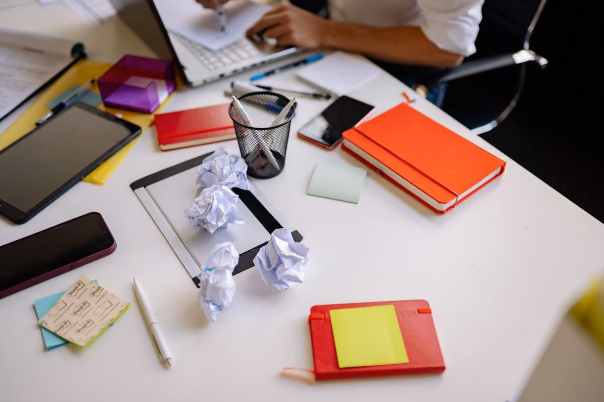 Mesa de trabalho desorganizada, com papéis amassados e anotações